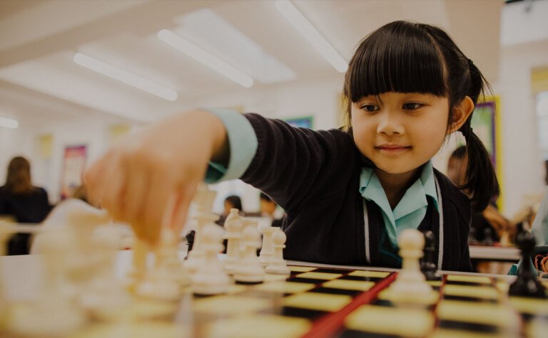 Lower junior school girl playing chess during co-curricular session at St Margaret's School