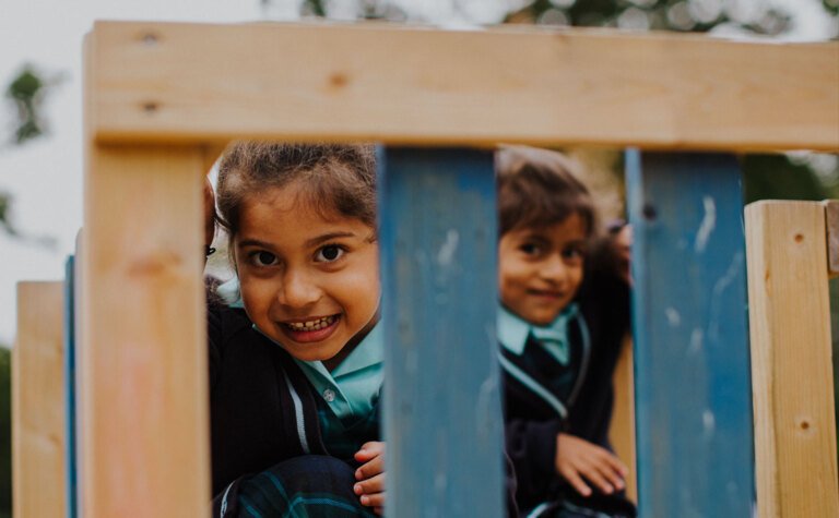 Two lower junior school girls smiling and happy outside at St Margaret's School Bushey