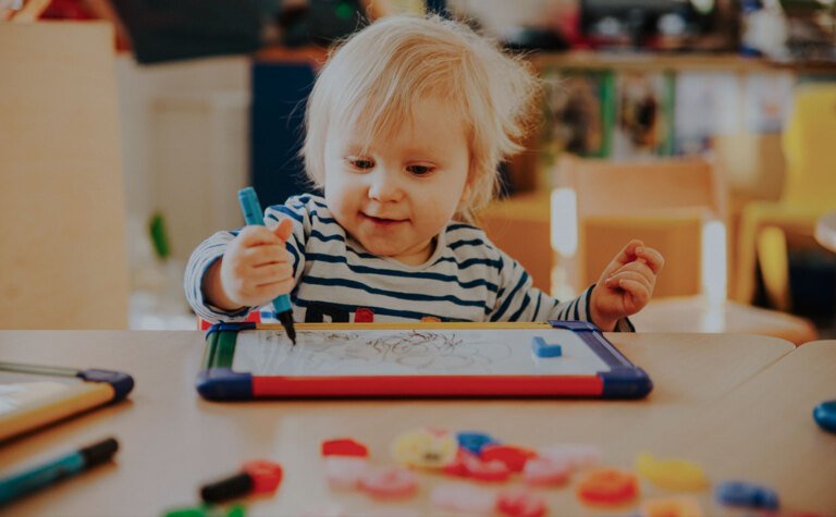 Nursery age child happily colouring at a table in the nursery school at St Margaret's