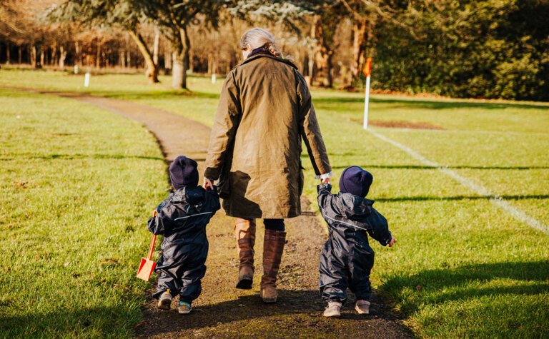 Staff member and two children taking a walk outside the Nursery at St Margaret's School Bushey