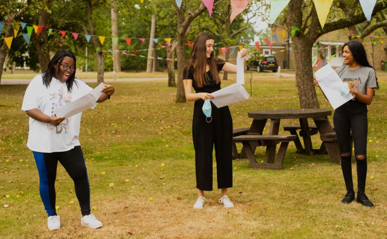Three excited students opening their exam results outside St Margaret's School Bushey