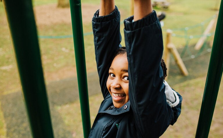 St Margaret's junior school girl smiling and swinging in playground