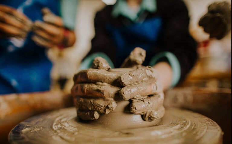 Close up of pupils hands around clay on pottery wheel at St Margaret's School