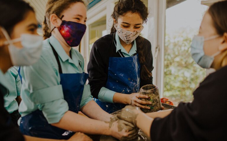 Senior school pupils laughing and enjoying pottery lesson at St Margaret's School