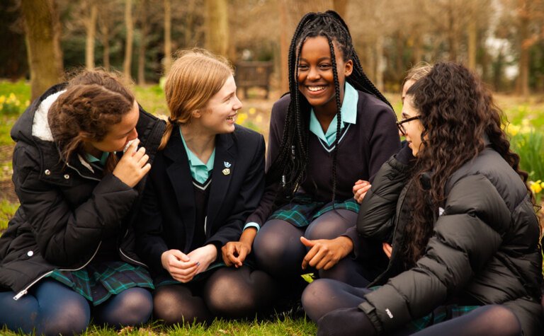Group of senior school students sitting on grass talking and laughing outside St Margaret's School