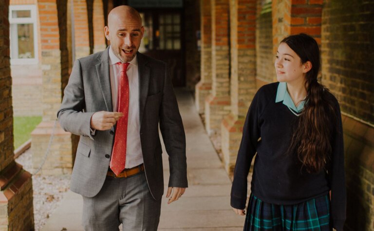 Senior school pupil walking and talking with St Margaret's School staff member