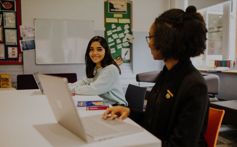 Two happy sixth form students talking in classroom at St Margaret's