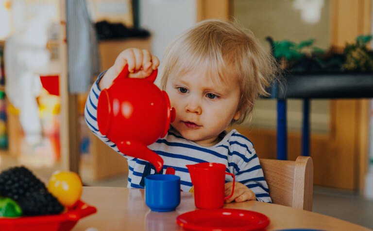 Nursery child pretending to pour tea at a tea party during after school care at St Margaret's School Bushey