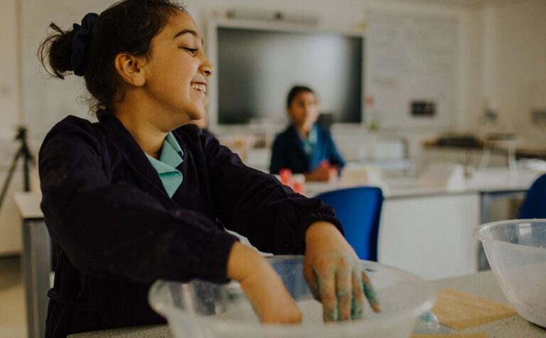 Upper junior school girl playing with colourful sand in classroom during after school care at St Margaret's School