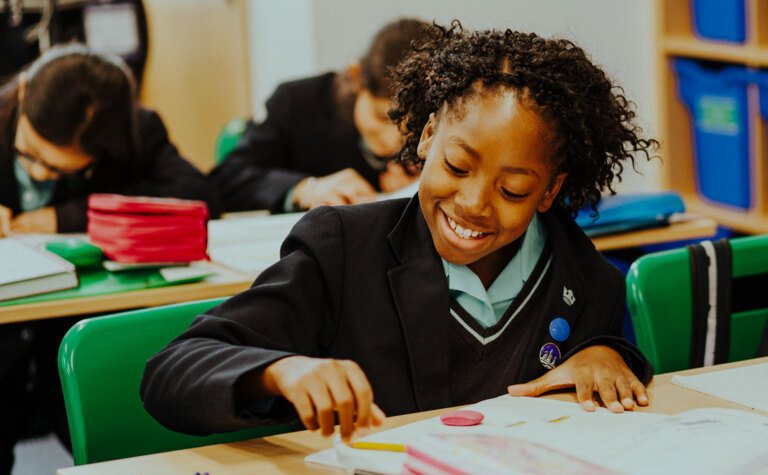 Upper junior school pupils writing in exercise books during classroom learning at St Margaret's School Bushey