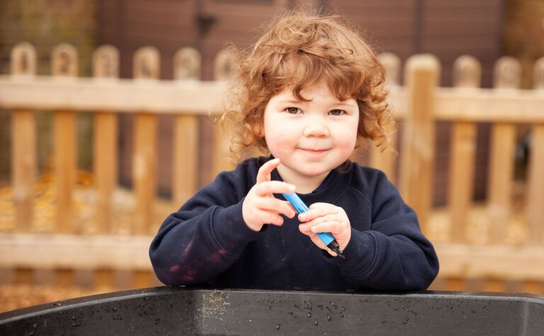 St Margaret's School Nursery child playing outside with a water tray in the Early Years play area