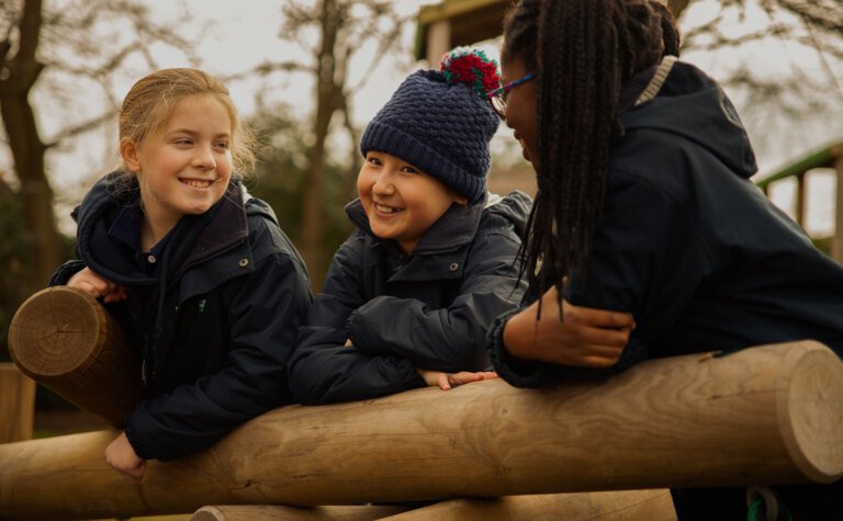 Three junior school pupils playing and having fun in the outdoor play area at St Margaret's School Bushey