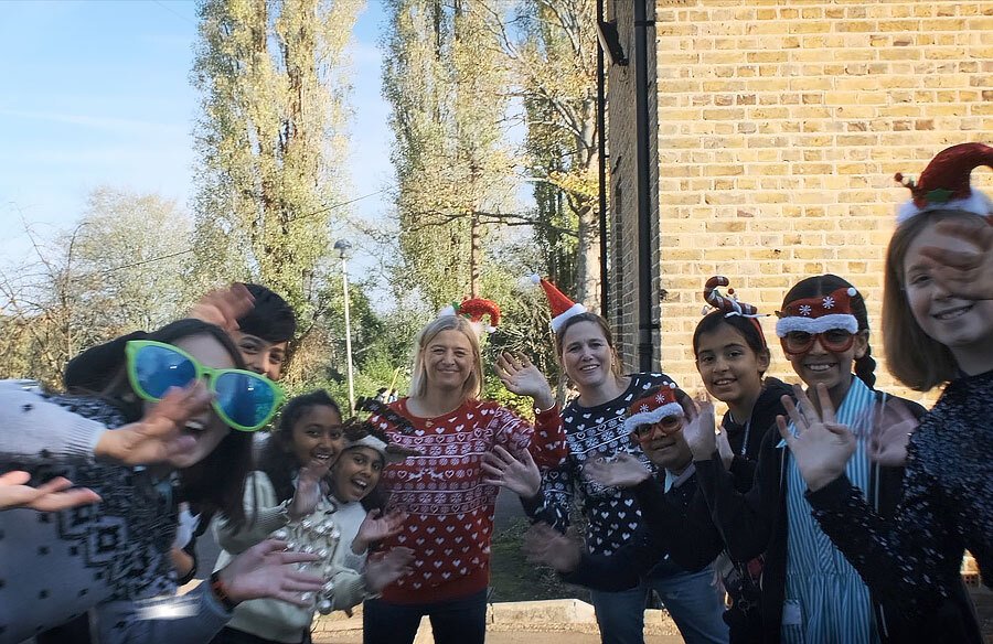 Group of children and staff waving and wearing Christmas hats