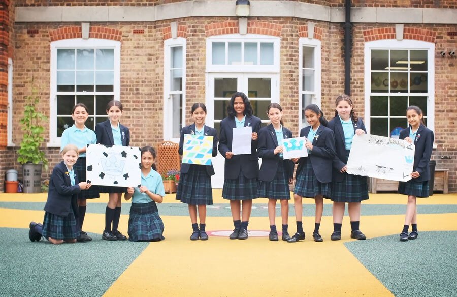 Group of Year 6 pupils outside Junior School holding examples of work