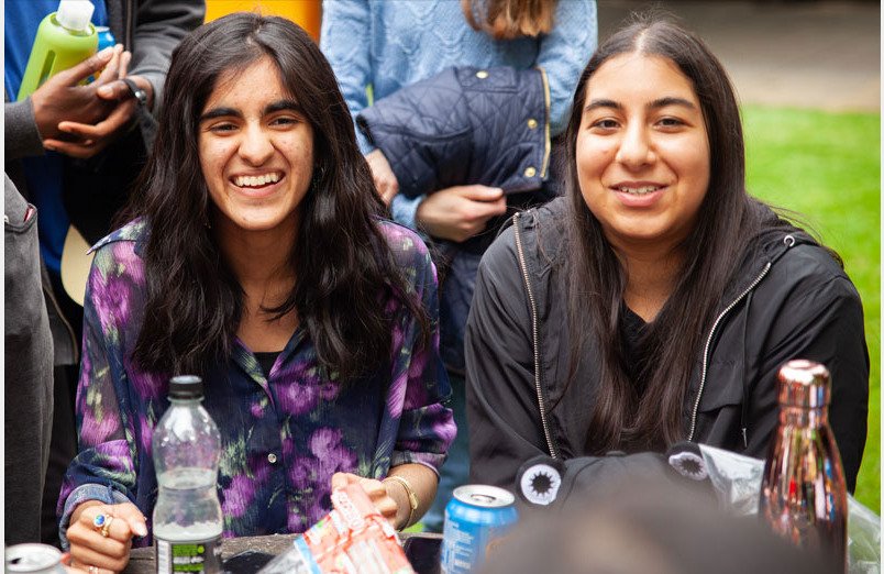 Two of St Margarets School Y13 Leavers laughing at party in orchard