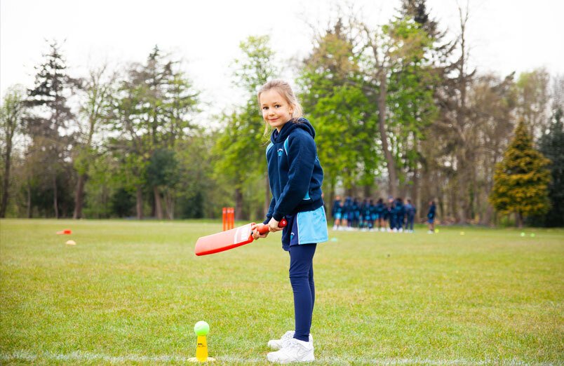 Young Junior School pupil at St Margarets School practising how to bat during a cricket lesson on rear playing fields
