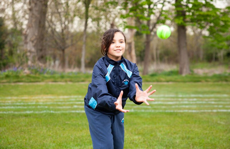 Young female pupil at St Margarets School catching a tennis ball during cricket lesson