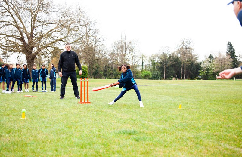 Junior School female pupil at St Margarets School batting during a cricket lesson on school playing field