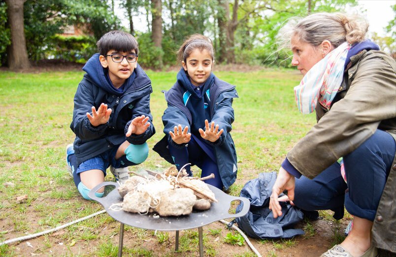 St Margarets School Outdoor Education lesson with two children and teacher round fire pit