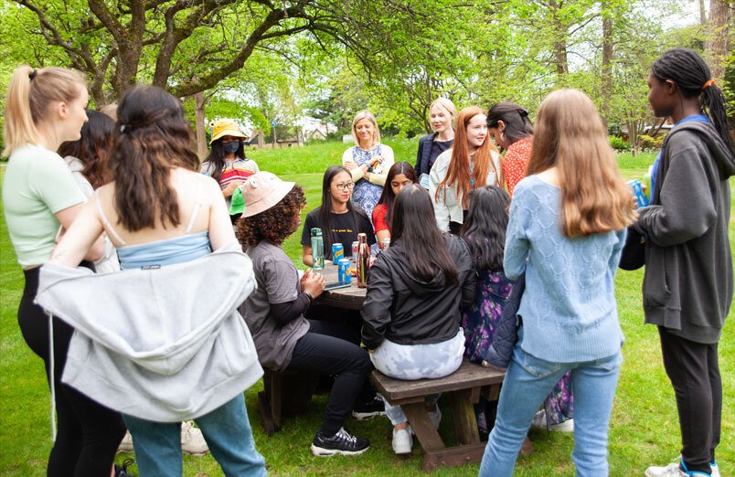 Group of St Margaret's Sixth Form pupils in orchard with the Head , Lara Péchard