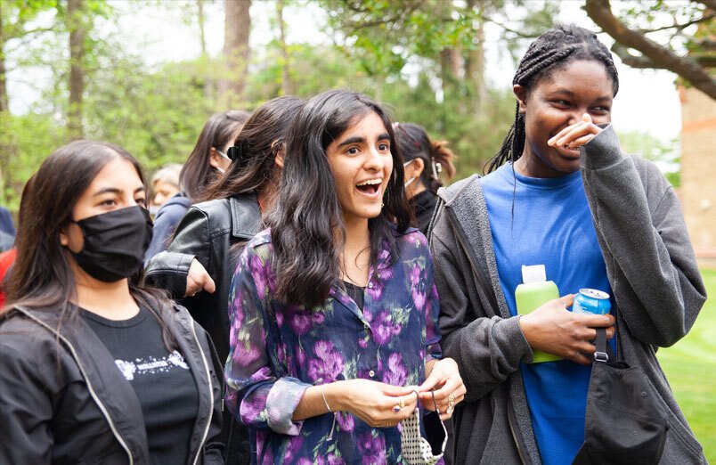 Three of St Margarets Sixth Form pupils laughing in orchard at Leaver's BBQ