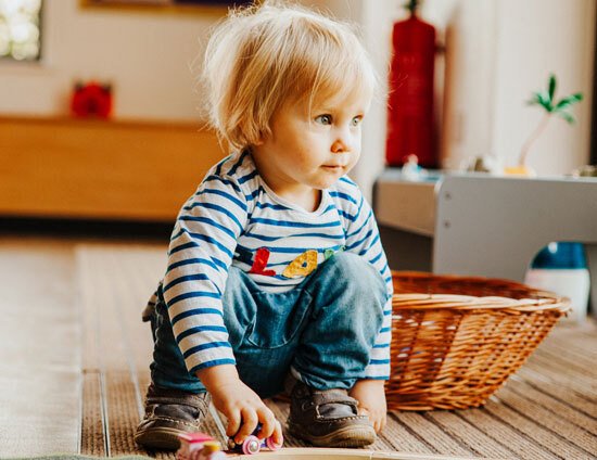 Nursery aged child playing with wooden train set in classroom at St Margaret's School Nursery in Bushey