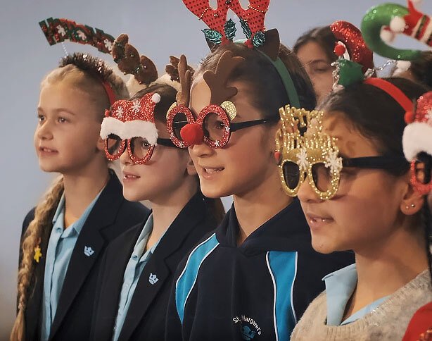 Group of St Margaret's School choir wearing Christmas glasses and headbands